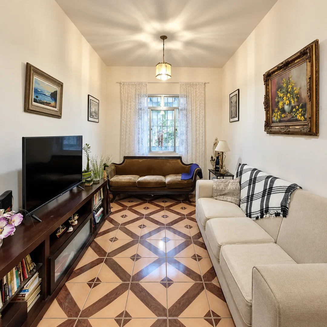 Sala de estar com piso em mosaico, sofás claros e janela ao fundo